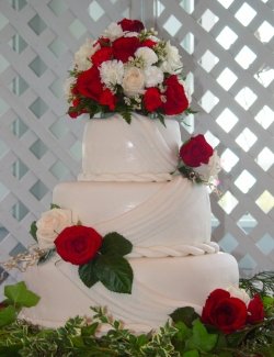 Stacked rolled fondant wedding cake with twists, drapes and fresh roses