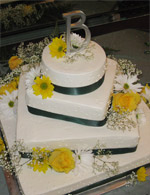 Top View - Daisies unite with yellow roses to make a lovely floral balance on single layer squares. A surpise round top make this a very unique and simple wedding cake with dramatic style.